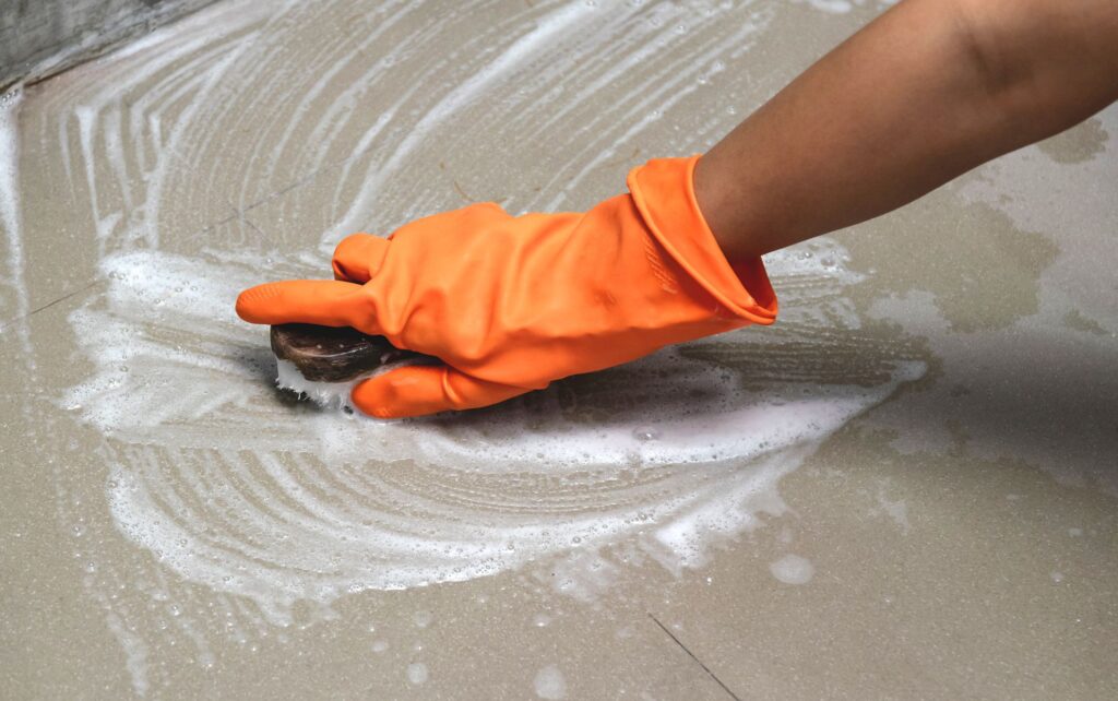 person cleaning floor wearing gloves