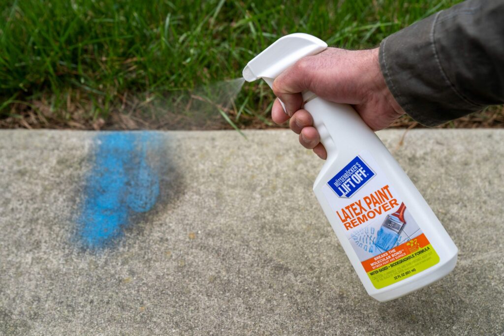 person spraying paint on concrete wall