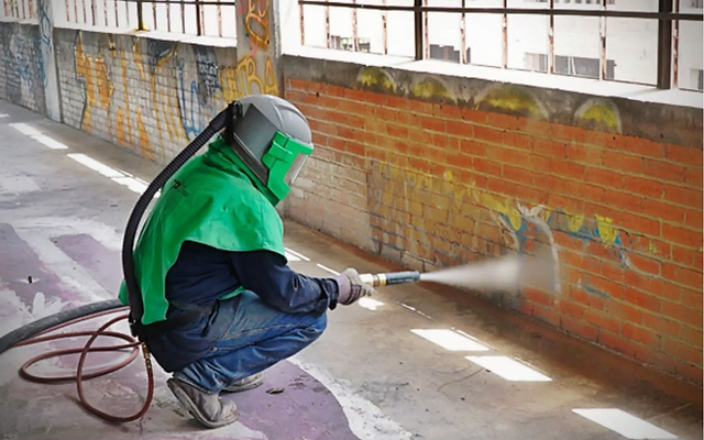 person equipped with paint safety vest and applying color in concrete wall