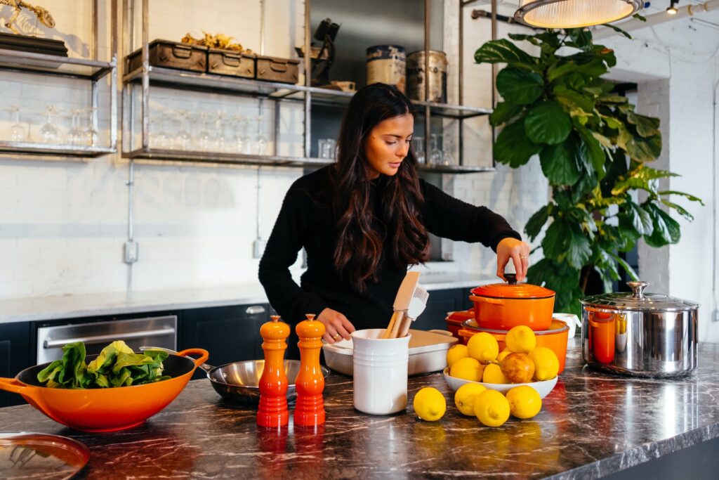 woman standing in front of fruits holding pot's lid
