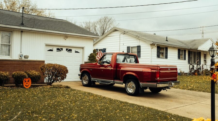 red single-cab pickup truck parking in front of garage during daytime