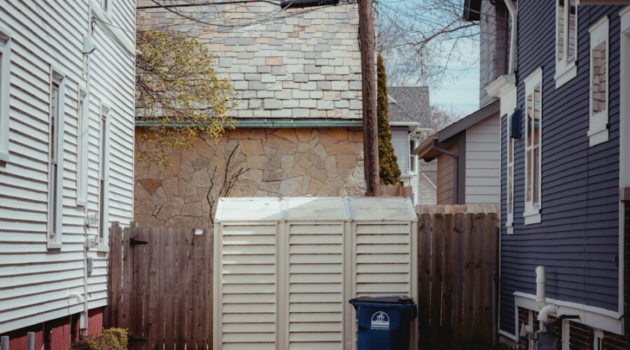 blue plastic trash bin beside brown brick wall